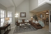 This three-floor home offers a thoughtfully arranged layout across its levels, blending functional design with comfortable living spaces. The main floor features a bright living area with a staircase highlighted by vaulted ceilings and large windows that invite natural light. The adjacent dining area includes a ceiling fan and a sliding glass door that opens to an outdoor view of the fenced yard, creating a seamless indoor-outdoor connection. The kitchen is outfitted with white cabinetry, granite-look countertops, wood-look flooring, and a full suite of appliances, offering an efficient and clean workspace. Upstairs, the carpeted bedrooms provide a restful retreat, each featuring ceiling fans, neutral tones, and generous natural light from multiple windows. A spacious walk-in closet offers ample storage, while a well-appointed bathroom with a granite vanity top and dark-framed mirror adds a refined touch. The finished basement extends the living space further, hosting a cozy lounge area with drop ceilings and recessed lighting, along with a secondary dining nook — ideal for entertaining or relaxation. Throughout, neutral color palettes, carpet flooring, and consistent design details create a cohesive and welcoming atmosphere across all three floors.