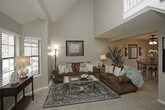 This three-floor home offers a thoughtfully arranged layout across its levels, blending functional design with comfortable living spaces. The main floor features a bright living area with a staircase highlighted by vaulted ceilings and large windows that invite natural light. The adjacent dining area includes a ceiling fan and a sliding glass door that opens to an outdoor view of the fenced yard, creating a seamless indoor-outdoor connection. The kitchen is outfitted with white cabinetry, granite-look countertops, wood-look flooring, and a full suite of appliances, offering an efficient and clean workspace. Upstairs, the carpeted bedrooms provide a restful retreat, each featuring ceiling fans, neutral tones, and generous natural light from multiple windows. A spacious walk-in closet offers ample storage, while a well-appointed bathroom with a granite vanity top and dark-framed mirror adds a refined touch. The finished basement extends the living space further, hosting a cozy lounge area with drop ceilings and recessed lighting, along with a secondary dining nook — ideal for entertaining or relaxation. Throughout, neutral color palettes, carpet flooring, and consistent design details create a cohesive and welcoming atmosphere across all three floors.