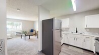 Located at 923 Maplewood Dr in Cedar Falls, Iowa, this one-bedroom, one-bathroom unit offers a thoughtfully designed single-floor layout that maximizes functionality within a compact footprint. The open-concept living and dining area features soft carpeting, neutral gray walls, and multiple windows that invite natural light and outdoor views of the surrounding greenery. A ceiling fan adds practical comfort to the living space.

The kitchen is well-equipped with white shaker-style cabinetry accented by matte black hardware, light marble-look countertops, and a full suite of stainless steel appliances including a refrigerator, range, and microwave. Wood-look luxury vinyl plank flooring runs throughout the kitchen, providing a clean contrast to the carpeted living areas. A compact dining nook with built-in shelving offers a dedicated space for meals.

The bedroom is a comfortable, carpeted retreat with a closet and a window that brings in natural light. Its understated design creates a calm and restful atmosphere. The bathroom features a walk-in shower with large-format gray tile surround and a clean white base, offering a modern and easy-to-maintain design. Throughout the unit, a consistent neutral color palette and textured ceilings contribute to a cohesive, move-in-ready aesthetic.