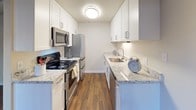This single-story residence offers a thoughtfully designed layout combining comfort and modern finishes throughout. Dark hardwood-style flooring flows seamlessly across the entire unit, creating a warm, cohesive aesthetic from room to room.

The living area is bright and open, featuring a ceiling fan and a full-width sliding glass door fitted with vertical blinds, providing direct access to an outdoor space and allowing generous natural light to fill the room. An adjacent area, partially divided by a half-wall, extends the living space and adds versatility to the floor plan.

The galley-style kitchen is well-equipped with white shaker cabinetry, granite-style countertops, a stainless steel undermount sink, and a full suite of stainless steel appliances, including a refrigerator, electric range, and microwave. The clean white finishes and under-cabinet lighting enhance both functionality and visual appeal.

The bedroom is a comfortable, well-lit space featuring its own ceiling fan, a natural light-admitting window with vertical blinds, and the same consistent hardwood-style flooring found throughout the unit.

The bathroom is finished with white cabinetry, a granite-topped vanity with an undermount sink, brushed nickel hardware, a large mirror, and a window for natural light, creating a clean and modern feel.