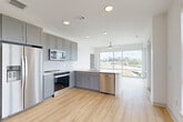 Located at 1450 Morrison Rd in Denver's vibrant 80204 corridor, this modern 2-bedroom, 2-bathroom residence offers a thoughtfully designed open-concept layout finished with light hardwood flooring throughout the main living areas. The kitchen is outfitted with gray shaker cabinetry, white tile backsplash, light quartz countertops, and a full suite of stainless steel appliances, including a refrigerator, range, microwave, and dishwasher. The kitchen flows seamlessly into the combined dining and living area, where floor-to-ceiling windows and a sliding glass door to a private balcony fill the space with natural light and frame sweeping views of the Denver skyline. A ceiling fan adds comfort to the airy living room. Both bedrooms are carpeted and feature large windows with city views and ceiling fans. The spacious primary bedroom includes ample closet space and access to a well-appointed bathroom with a glass-enclosed marble tile shower, wood-look flooring, and gray vanity cabinetry. Additional highlights include a dedicated laundry area, utility room, three closets, and a bright, clean hallway connecting all rooms. The crisp white walls and recessed lighting throughout lend a clean, contemporary aesthetic to the entire residence.