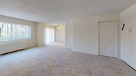 Located at 2445 Lyttonsville Rd in Silver Spring, MD, this single-floor residence offers a thoughtfully arranged layout designed for comfortable everyday living. The kitchen is well-appointed with rich warm-toned wood cabinetry, granite-style countertops, and white appliances including a gas range, dishwasher, and under-cabinet range hood, providing ample storage and workspace for cooking. The living and dining areas are generously sized, featuring soft wall-to-wall carpeting, neutral white walls, and a textured ceiling throughout. Large windows dressed with vertical blinds allow natural light to fill the space while offering views of the surrounding greenery. A ceiling fan adds to the comfort of the main living area, which flows openly into adjoining spaces. The bedrooms are well-proportioned with plush carpeting and include closet storage. One bedroom features a walk-in closet visible through an open door. The bathroom is finished with full tile surround in the tub-shower combination, a vanity with a white countertop and mirrored medicine cabinet above, and classic tile accents on the walls. Overall, the unit presents a clean, functional, and comfortable living environment in a convenient Silver Spring location.