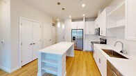Located at 35205 Tupelo Cir in Frankford, Delaware, this single-floor, one-bedroom, one-bathroom home offers a thoughtfully designed layout that maximizes every square foot. The open-concept kitchen and living area serves as the heart of the home, featuring crisp white shaker cabinetry, stainless steel appliances including a French door refrigerator, electric range, microwave, and dishwasher, all set against a clean white backsplash and light wood-style flooring. A white center island with built-in shelving provides additional prep space and storage, while pendant lighting and recessed lights create a bright, welcoming atmosphere. The living area extends naturally from the kitchen and opens to the outdoors through a glass door, offering views of the surrounding greenery and access to a wood-decked exterior space. The bedroom is a comfortable retreat with soft carpet flooring, a ceiling fan, and a large window that brings in ample natural light and outdoor views. The bathroom is clean and functional, featuring a vanity, toilet, and a glass-enclosed shower, with direct access to a walk-in closet with built-in shelving. Three closets in total provide generous storage throughout. A dedicated utility room rounds out the practical offerings of this well-appointed home.