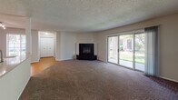 Located at 1373 Ivy Ln in Naperville, Illinois, this single-floor residence offers a well-organized layout designed for comfortable living. The generously sized living room serves as the heart of the home, featuring a striking black tile fireplace, plush wall-to-wall carpeting, and a textured ceiling. Large sliding glass doors flood the space with natural light and provide views of the surrounding greenery, creating a bright and open atmosphere. A structural column subtly defines the transition between the living area and the adjacent spaces. The kitchen is efficiently designed with warm-toned wood cabinetry, light countertops, hardwood-style flooring, and a full suite of stainless steel appliances, including a refrigerator, electric range, over-the-range microwave, and dishwasher. The bedrooms are carpeted and well-lit by natural light from windows, offering a calm and restful environment. Closet space is readily accessible in the bedroom hallway. Two full bathrooms serve the residence; one features warm wood vanity cabinetry with a stone-look countertop and tile flooring, while the other offers a clean, minimal design with a tub-shower combination. Throughout the home, neutral tones and consistent finishes contribute to a cohesive and practical living environment.