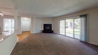 Located at 1373 Ivy Ln in Naperville, Illinois, this single-floor residence offers a well-organized layout designed for comfortable living. The generously sized living room serves as the heart of the home, featuring a striking black tile fireplace, plush wall-to-wall carpeting, and a textured ceiling. Large sliding glass doors flood the space with natural light and provide views of the surrounding greenery, creating a bright and open atmosphere. A structural column subtly defines the transition between the living area and the adjacent spaces. The kitchen is efficiently designed with warm-toned wood cabinetry, light countertops, hardwood-style flooring, and a full suite of stainless steel appliances, including a refrigerator, electric range, over-the-range microwave, and dishwasher. The bedrooms are carpeted and well-lit by natural light from windows, offering a calm and restful environment. Closet space is readily accessible in the bedroom hallway. Two full bathrooms serve the residence; one features warm wood vanity cabinetry with a stone-look countertop and tile flooring, while the other offers a clean, minimal design with a tub-shower combination. Throughout the home, neutral tones and consistent finishes contribute to a cohesive and practical living environment.