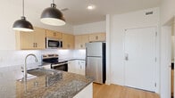 Located at 2820 W Broad St in Richmond, VA, this well-appointed one-bedroom, one-bathroom unit offers a thoughtfully designed open-concept layout with modern finishes throughout. Light hardwood flooring flows seamlessly across the living spaces, creating a warm and cohesive aesthetic.

The kitchen and living area form the heart of the unit. The kitchen is equipped with a full suite of stainless steel appliances, including a refrigerator, electric range, microwave, and dishwasher. Light maple cabinetry pairs with white lower cabinets and dark granite countertops, while a classic white subway tile backsplash adds a clean, contemporary touch. A central island with pendant lighting overhead provides additional prep space and casual seating.

The bedroom is a bright, comfortable retreat featuring large windows that invite natural light and offer elevated views of the surrounding Richmond neighborhood. A ceiling fan adds functionality and comfort.

The bathroom is finished with a warm wood-toned vanity, dark granite countertop, and a striking blue tile surround in the tub/shower combination, complemented by stone-look flooring. An in-unit laundry closet with a stacked washer and dryer adds everyday convenience. The unit's clean, modern design makes it a functional and stylish home in the heart of Richmond.