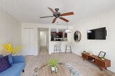Located in Kissimmee, FL, this two-story, 2-bedroom, 2-bathroom home is thoughtfully designed across two evenly distributed floors. The main level opens into a combined living and dining area with plush carpeting, a ceiling fan, and a seamless connection to the kitchen via a breakfast bar with counter-height seating. The kitchen features rich dark cabinetry, granite-style countertops, tile flooring, and black appliances. A hallway with louvered closet doors and tile flooring connects the main living spaces efficiently. Sliding glass access leads to a balcony overlooking lush tropical landscaping and palm trees. Upstairs, both bedrooms offer carpet flooring, ceiling fans, crown molding, and ample natural light through large windows with vertical blinds. The spacious primary bedroom comfortably accommodates a king-size bed. Both bathrooms are finished with dark wood vanities, granite countertops, tile flooring, and large mirrors. Four closets throughout the home provide generous storage. The neutral color palette and consistent finishes create a cohesive, inviting atmosphere throughout the entire space.