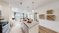 This thoughtfully laid-out one-bedroom, one-bathroom residence offers a bright and modern living experience across a single floor. The open-concept kitchen and living area serves as the heart of the home, anchored by a granite-topped island with an undermount sink and bar seating for two. Pendant lighting hangs above the island, complementing recessed ceiling lights throughout. The kitchen is equipped with stainless steel appliances, white cabinetry, and a tile backsplash, creating a clean and functional workspace. Wood-style flooring flows seamlessly throughout the main living areas, adding warmth to the contemporary design.

The living room receives generous natural light through large windows and features a ceiling fan, creating a comfortable and airy atmosphere. The spacious primary bedroom also benefits from large windows with outdoor views, a ceiling fan, and direct access to a dedicated closet. The en-suite bathroom is finished in crisp white tiling and includes a full soaking tub with shower, white cabinetry, and granite countertops. An entrance area and additional closet provide practical storage solutions. The overall aesthetic is clean, modern, and welcoming throughout.