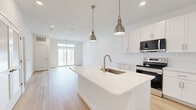 This well-appointed one-bedroom, one-bathroom unit at 2220 N Susquehanna Trail in York offers a thoughtfully designed layout across a single floor. The open-concept kitchen and living area serves as the heart of the home, finished with light hardwood flooring that extends throughout the main living spaces. The kitchen is equipped with crisp white shaker cabinetry, a full suite of stainless steel appliances including a refrigerator, electric range, and built-in microwave, complemented by a central island with a white quartz countertop, undermount sink, and stylish pendant lighting. The living area is bright and airy, featuring sliding glass doors topped with transom windows that open to a private balcony, allowing natural light to pour in. The spacious bedroom features plush wall-to-wall carpeting, a ceiling fan, and a window with blinds offering additional natural light. The bathroom is clean and modern, with light wood-look flooring, a tiled tub-shower combination with brushed nickel fixtures, and a white vanity with ample counter space. Throughout the unit, crisp white walls, recessed lighting, and a neutral palette create a cohesive, contemporary ambiance ideal for comfortable everyday living.