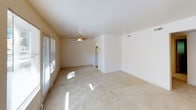 This two-bedroom, one-bathroom apartment is designed for comfortable, functional living across a single floor. The spacious living area features neutral-toned carpet, a ceiling fan, and large windows with views of lush greenery, allowing natural light to fill the room. A sliding glass door provides additional brightness and outdoor access. Baseboard heating is present throughout the unit, ensuring consistent warmth. The kitchen is efficiently laid out with white cabinetry offering generous storage, a coil-burner electric range, refrigerator, and a stainless steel double sink, all beneath a drop ceiling with recessed lighting. Both bedrooms are well-proportioned, carpeted, and receive natural light through windows overlooking the outdoors. One bedroom includes a sliding-door closet with a full-length hanging rod for ample storage. The bathroom features a full tub-shower combination with white tile surround, a toilet, and grab bar. A dedicated in-unit laundry area houses a full-size Whirlpool washer and dryer. The entry foyer includes an adjacent closet, offering a tidy transition into the home. This apartment delivers a clean, straightforward layout suited for everyday living.