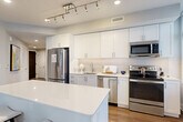 Located at 3400 South Clark Street in Arlington, VA, this well-appointed 2-bedroom, 2-bathroom residence offers a thoughtfully designed single-floor layout. The open-concept living, dining, and kitchen area serves as the heart of the home, featuring warm hardwood-style flooring and neutral tones throughout. The kitchen is a standout, equipped with stainless steel appliances including a refrigerator, range, microwave, and dishwasher, complemented by crisp white shaker cabinetry, a subway tile backsplash, quartz countertops, and a center island with bar seating. Large windows flood the kitchen and living areas with natural light. The spacious primary bedroom is carpeted for comfort and includes multiple closets with built-in shelving systems, offering generous storage. Its en-suite bathroom features a glass-enclosed shower with white tile surround and elegant tile flooring. The second bathroom offers a full tub-shower combination with matching tile finishes and a white vanity. A dedicated hallway with additional closets and an in-unit laundry area add everyday convenience. The clean, modern aesthetic is carried consistently throughout, making this a functional and refined urban residence.