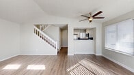 Located at 12786 E Pacific Dr in Aurora, CO, this two-story home offers a well-organized layout across two floors. The main level features a bright, open living room with vaulted ceilings, a ceiling fan, and hardwood-style flooring that runs throughout. Natural light pours in through multiple windows and transom windows flanking the front door, complementing a cozy fireplace with a tile surround—an inviting focal point of the space. A sliding glass door provides additional light and access to the outdoors. The kitchen is positioned just off the living area and features white cabinetry, a blue-gray subway tile backsplash, dark countertops, and stainless steel appliances including a refrigerator, range, and over-the-range microwave. Plantation shutters on the kitchen window add a clean, finished touch. A white-railed staircase leads to the upper level, which is more intimate in scale and houses the two bedrooms and two full bathrooms. Both bedrooms feature plush carpeting, neutral walls, and windows with blinds that allow for natural light. Each bathroom is outfitted with a full tub-shower combination and wood-style flooring. Two closets provide practical storage throughout. The overall aesthetic is clean, neutral, and move-in ready.