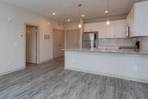 This single-floor unit presents a cohesive, modern design highlighted by a neutral color palette and quality finishes throughout. The kitchen serves as a central feature, equipped with stainless steel appliances including a refrigerator, range, and built-in microwave. White shaker-style cabinetry extends to the ceiling, complemented by a white subway tile backsplash and granite countertops. A large island with an undermount sink and pendant lighting above adds both functionality and visual appeal. Wood-look flooring runs throughout the kitchen and living areas.

The bedrooms are carpeted and bathed in natural light from windows with views of surrounding greenery. Ceiling fans provide additional comfort, and the rooms offer generous proportions suitable for varied furniture arrangements.

Two bathrooms echo the kitchen's design language, featuring white cabinetry, granite-topped vanities, and wood-look flooring. One bathroom includes a tub-shower combination with white subway tile surround, while the second features a double-sink vanity with brushed nickel fixtures and well-lit mirrors.

Storage is well addressed with a dedicated walk-in closet outfitted with white wire shelving and a hanging rod system. The overall ambiance is clean, bright, and move-in ready.