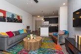 This single-floor Atlanta residence showcases a contemporary design with a cohesive blend of dark cabinetry, granite countertops, and wood-look flooring throughout. The kitchen serves as a centerpiece, featuring dark flat-front cabinets with brushed nickel hardware, a white subway tile backsplash, full stainless steel appliances including a French door refrigerator, microwave, and range, and a spacious granite-topped island with bar seating and pendant lighting overhead. The kitchen opens naturally toward the living area, which benefits from natural light through large windows and French doors, a ceiling fan, and a textured accent wall that adds visual depth.

Two bedrooms provide comfortable retreats, each with windows admitting natural light and wood-look flooring. The primary bathroom includes a walk-in glass shower, dark vanity with granite countertop, and direct access to a walk-in closet. A second full bathroom offers a tub-shower combination with white tile surround, a dark vanity with granite countertop, and a framed mirror. The overall ambiance is modern and polished, with consistent finishes tying each space together cohesively.