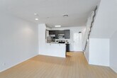 Located at 920 Wilcox Ave in the heart of Los Angeles, CA 90038, this two-story residence offers a clean, modern aesthetic throughout. The main floor greets you with a bright, open-concept living and dining area finished in light hardwood flooring that reflects natural light streaming through large windows. A tiled fireplace anchors one corner of the living space, adding warmth and character. The kitchen is thoughtfully designed with a peninsula breakfast bar, dark espresso cabinetry, light countertops, and stainless steel appliances including a refrigerator, range, microwave, and dishwasher — all seamlessly integrated into the open layout. A staircase with a classic white balustrade leads to the upper level, where the bedrooms are located. Each bedroom features dark hardwood-style flooring, neutral walls, and windows that frame views of the surrounding Los Angeles cityscape and treeline. One bedroom includes a mirrored sliding closet, while another offers walk-in closet access. Two full bathrooms, each equipped with a tub and glass-door shower enclosure, serve the home. The overall ambiance is contemporary and light-filled, making this Hollywood-area residence a functional and stylish urban home.