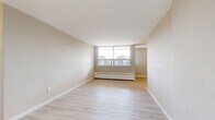 Located on the third floor at 552 Birchmount Rd in Toronto's Scarborough district, this one-bedroom, one-bathroom unit offers a clean, functional layout across a single floor. Light-toned hardwood flooring runs throughout the living and sleeping areas, creating a bright and cohesive aesthetic complemented by neutral warm-beige walls and crisp white baseboards.

The open living room is a comfortable and well-lit space, anchored by a large picture window that frames outdoor views and allows generous natural light to fill the room. A baseboard heating unit runs beneath the window, providing efficient warmth. The space flows naturally toward the rest of the unit, maintaining an easy sense of continuity.

The galley-style kitchen features white cabinetry along both walls, offering ample storage. It is equipped with stainless steel appliances including a refrigerator and electric range, with granite-style countertops and light ceramic tile flooring underfoot. Overhead lighting ensures the kitchen is well-illuminated throughout.

The bedroom is a well-proportioned private retreat with its own window overlooking the surroundings, continuing the light hardwood floors and neutral palette. A built-in closet with sliding doors provides practical storage.

The bathroom is finished with classic white wall tiles surrounding a full bathtub and shower combination, complemented by a mosaic tile floor with warm brown accents, a toilet, and a sink — offering a tidy, functional space.