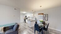 This single-floor residence offers 2 bedrooms and 1 bathroom within a thoughtfully designed, efficient layout. The open-concept living and dining area flows seamlessly into the kitchen, creating a bright and connected space. Light gray laminate flooring runs throughout, complementing the neutral wall tones and contributing to a clean, contemporary aesthetic. Ceiling fans in the living and bedroom areas add both function and style.

The kitchen is a standout feature, showcasing white shaker-style cabinetry, dark countertops, a classic white subway tile backsplash, and stainless steel appliances including a range, microwave, and dishwasher. A peninsula with seating potential separates the kitchen from the dining area, which is illuminated by a warm pendant light fixture.

The living room is comfortably sized with a window that allows natural light to fill the space. Both bedrooms are well-proportioned, each equipped with a ceiling fan and windows with blinds. The primary bedroom offers generous closet storage. The second bedroom also includes closet access and natural light.

The bathroom is neatly finished with a white vanity, a taupe countertop, a framed mirror, and marble-look tile flooring. A tub-shower combination completes the space. A dedicated closet provides additional storage within the unit.