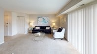 This single-floor residence offers a thoughtfully designed layout that balances comfort and functionality. The living room serves as the heart of the home, featuring plush carpeting, neutral walls, and large sliding glass doors fitted with vertical blinds that flood the space with natural light and provide views of the outdoors. The open flow connects seamlessly to a dedicated dining area, which features a pendant light fixture overhead and neutral carpeted flooring.

The kitchen is outfitted with rich dark-wood cabinetry, dark stone-look countertops, a gas range, dishwasher, and a double sink, all complemented by light tile flooring that adds a clean, practical finish.

The primary bedroom is generously proportioned, offering plush carpeting, multiple windows dressed with teal drapes, and ample room for a full furniture arrangement. The secondary bedroom, also carpeted, provides a comfortable and versatile space with a window for natural light.

Two bathrooms serve the residence, each featuring light tile floors, dark wood vanities, and clean white fixtures. One bathroom includes a shower with a decorative curtain, while the other presents a half-bath configuration. Together, the rooms create a cohesive, welcoming atmosphere throughout.