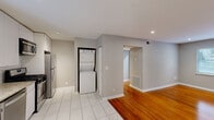 Located in the desirable Peachtree Hills neighborhood of Atlanta, GA, this 2-bedroom, 1-bathroom home offers a thoughtfully designed single-floor layout that maximizes comfort and functionality. Rich, warm-toned hardwood floors run throughout the living areas and bedrooms, creating a cohesive and inviting ambiance, while large-format tile flooring defines the kitchen and laundry area.

The modern kitchen is a standout feature, showcasing sleek white cabinetry extending to the ceiling, granite countertops, a classic subway tile backsplash, and a full suite of stainless steel appliances including a gas range, dishwasher, microwave, and refrigerator. Natural light filters in through a window fitted with blinds, brightening the space. Conveniently tucked adjacent to the kitchen is a stacked in-unit washer and dryer.

Both bedrooms feature the same warm hardwood flooring, recessed or ceiling-mounted lighting, and closets with built-in shelving. One bedroom enjoys a window with a lush outdoor view, adding a touch of greenery to the space.

The bathroom offers a clean, spa-like aesthetic with floor-to-ceiling marble-style tile surrounding a soaking tub and shower combo, complemented by a window that brings in natural light. Neutral gray walls throughout the home provide a versatile backdrop, completing this well-appointed Atlanta residence.