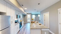 This well-designed studio in Birmingham, Alabama, offers a thoughtfully arranged single-floor layout that maximizes every square foot. The open-concept living area seamlessly connects the kitchen, dining, and living spaces, creating a functional and cohesive environment. Light wood-style flooring runs throughout, complementing the neutral gray and beige tones on the walls.

The kitchen is a standout feature, showcasing white shaker-style cabinetry, a subway tile backsplash, granite countertops, and a full suite of stainless steel appliances including a refrigerator, range, and over-the-range microwave. A large kitchen island with granite countertops provides additional prep and dining space, accented by pendant lighting above.

The living area benefits from multiple windows with horizontal blinds, allowing ample natural light to fill the space. A ceiling fan adds comfort and practicality. A private entry door leads to what appears to be a balcony or outdoor access.

The bathroom is clean and modern, featuring white cabinetry, granite countertops, a rectangular undermount sink, and wood-look tile flooring. Two closets provide practical storage solutions, including a spacious walk-in style closet with wire shelving. The overall design is cohesive, contemporary, and move-in ready.