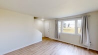 Located in the Albert Park neighbourhood of Calgary, Alberta, this three-storey home offers a practical and well-organized layout across three levels. The main floor features a bright living room with light hardwood-style flooring, large windows framing outdoor greenery, and a staircase leading to the upper level. The kitchen is outfitted with white cabinetry, tile backsplash, a countertop with an undermount sink, and tile flooring, and is equipped with a refrigerator and electric range. Natural light flows generously through multiple windows, providing pleasant views of the surrounding landscape.

Upstairs, three bedrooms are finished with light hardwood-style flooring and neutral white walls, creating a clean and airy atmosphere. The primary bedroom offers a comfortable footprint with built-in closet storage. A full bathroom on the upper floor features wood-style flooring, a bathtub with shower, a toilet, and overhead cabinet storage, with a frosted window providing natural light. Each floor maintains a consistent, understated aesthetic throughout.

The unfinished basement provides additional utility space, featuring concrete floors, exposed wooden ceiling joists, and concrete walls — offering potential for future development or ample storage needs.