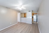 Located at 2302 W Loop 289 Frontage Rd in Lubbock, TX, this single-floor unit offers a functional and straightforward layout designed for comfortable everyday living. The open living area is finished with light wood-style flooring that extends throughout the main spaces, creating a clean and cohesive look. A textured ceiling and ceiling fan add practical comfort to the living room, which also benefits from a window that allows natural light to filter in. The kitchen is positioned behind a half-wall pass-through counter, providing a sense of separation while maintaining an open connection to the living area. Warm wood-toned cabinetry lines the kitchen walls, complemented by dark granite-style countertops and standard appliances including a range and refrigerator. A utility area with additional appliance hookups is accessible off the kitchen. The bedroom features plush carpeting, vertical blinds over a large window, and a textured ceiling, offering a quieter, more private retreat. A second room with wood-style flooring, a ceiling fan, and a window overlooking the exterior rounds out the living spaces. Overall, the unit presents a practical and well-maintained environment suited for daily living in west Lubbock.