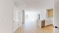 Located at 100 Avenue G in Bayonne, NJ, this modern 2-bedroom, 2-bathroom residence offers a thoughtfully designed open-concept layout finished with light wood flooring throughout the main living areas. The combined kitchen and living room serves as the heart of the home, where a sleek kitchen island with an undermount sink and integrated dishwasher anchors the space. The kitchen is well-appointed with two-tone cabinetry — warm wood uppers paired with crisp white lower cabinets — complemented by a subway tile backsplash and stainless steel appliances including a French door refrigerator and microwave. Recessed lighting illuminates the open layout, which flows seamlessly into a bright living area featuring large windows that invite generous natural light and outdoor views. Both bedrooms are comfortably sized, each with light wood flooring, neutral walls, and windows offering views of the surrounding community. The generously proportioned primary bedroom provides ample space for a full suite of furniture. The two bathrooms are finished with large-format tile flooring, warm wood vanity cabinetry, white countertops, and illuminated mirrors. A hallway connects the private quarters, maintaining a clean and functional flow throughout the residence.