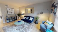 This well-appointed two-story residence offers 2 bedrooms and 1.5 bathrooms, thoughtfully designed across two levels. The main living area is bright and inviting, featuring light tile flooring and a contemporary aesthetic. The living room is highlighted by a bold navy velvet sofa, a plush area rug, a glass oval coffee table, and a gold-framed wall mirror, creating a cohesive and stylish atmosphere. Large windows with blinds allow natural light to fill the space. Adjacent to the living area, the dining space includes a glass-top table with upholstered chairs and a decorative round mirror with a sculpted silver frame, complemented by wainscoting detail on the walls.

The kitchen is equipped with dark cabinetry, light countertops, a stainless steel dishwasher, and a range, offering a functional layout with ample storage. The bedrooms are located upstairs and feature warm hardwood flooring, natural light from well-positioned windows, and generous space for furnishings. A full bathroom with a tiled tub-shower combination serves the upper level, while a half bath provides added convenience. The staircase connects the two levels seamlessly, making this a practical and comfortable multi-level home.