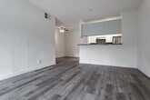 Located at 11657 Oxnard St in the North Hollywood neighborhood of Los Angeles, this single-floor unit offers a clean, contemporary living environment with consistent wood-style flooring carried throughout every room, creating a cohesive and easy-to-maintain aesthetic.

The open living area is bright and welcoming, highlighted by a ceiling fan overhead and a large sliding glass door fitted with vertical blinds that allows generous natural light to fill the space. The adjacent bedroom continues the light-filled theme, featuring its own sliding door or large window with vertical blinds that invite outdoor views and additional sunlight.

The kitchen is well-appointed with white cabinetry, granite-style countertops, a mosaic tile backsplash, and stainless steel appliances including a gas range and dishwasher. A black refrigerator completes the functional lineup, making this a fully equipped cooking space arranged in a practical galley configuration.

The bathroom is thoughtfully finished with wood-look tile flooring, a granite-topped vanity, and a full tub-shower combination clad in elegant linear stone-style tile, lending a refined, spa-like quality to the space.

Throughout the unit, neutral wall tones, textured ceilings, and consistent flooring contribute to a clean and modern ambiance suited to a variety of lifestyles.