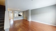Located at 400 Ivy Meadow Ln in Durham, NC, this two-floor residence offers a well-organized layout designed for comfortable everyday living. The main level features a generously sized open living area finished with rich hardwood flooring and neutral gray walls that create a clean, modern aesthetic. A pass-through window connects the living space to the kitchen, which is equipped with white cabinetry, granite countertops, a brown subway tile backsplash, and stainless steel appliances. A half bathroom on the main level adds convenience for guests. A staircase leads to the upper level, where carpeted flooring provides a softer feel underfoot. The upper floor includes an open room that functions well as a bedroom or flexible living space, accompanied by a full bathroom featuring a granite-topped vanity with white cabinetry, a large mirror, and hardwood flooring. A second bathroom on this level offers additional functionality. Natural light filters through windows on both floors, enhancing the bright, open atmosphere throughout. The layout flows logically between levels, making efficient use of the available space across the entire home.