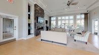 Located at 5825 Addison Park Dr in Huntsville, AL, this single-story clubhouse presents a thoughtfully designed communal space defined by soaring tray ceilings adorned with detailed crown molding. The open layout is anchored by a dramatic floor-to-ceiling tiled fireplace feature wall, finished in rich dark slate tones and paired with a wall-mounted television, creating a striking focal point. Built-in display niches flank the fireplace, adding architectural depth and visual interest.

Light hardwood flooring extends throughout the main gathering area, which accommodates generous lounge seating arranged to encourage conversation and relaxation. A bank of large windows along one wall floods the space with natural light while offering views of the surrounding outdoor areas. Ceiling fans with modern fixtures complement the recessed lighting overhead.

A dedicated workspace area features a private desk with an ergonomic chair, while a separate meeting nook with a round table and upholstered chairs provides an ideal setting for small group discussions. This area is distinguished by soft teal accent walls and framed artwork. Large glass entry doors with transom windows reinforce the sense of openness and connectivity, making this a welcoming and versatile community gathering space.