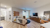 Located at 5727 North 7th Street in Phoenix, AZ, this one-bedroom, one-bathroom residence offers a thoughtfully designed layout with modern finishes throughout. The open-concept kitchen and living area serves as the heart of the home, where light wood-tone flooring, recessed lighting, and a glass-panel door flood the space with natural light. The kitchen is appointed with two-tone cabinetry — white uppers paired with gray lowers — stainless steel appliances including a full-size refrigerator, microwave, and range, as well as a dark tile backsplash and a central island with a white quartz countertop and bar seating. Pendant lighting over the island adds a contemporary touch. The living area flows naturally from the kitchen, featuring a glass door that opens to the outside and provides additional natural light. The bedroom offers a calm, neutral palette with plush carpet flooring, a ceiling fan, a window with natural light, and direct access to a dedicated walk-in closet equipped with multi-tier hanging rods and shelving. The bathroom features a glass-enclosed walk-in shower, a gray vanity with white countertop, wood-look tile flooring, and an LED-lit mirror, delivering a clean and functional design.