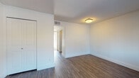 Located at 1300 S Pleasant Valley Rd in Austin, TX, this single-floor unit offers a clean, modern layout designed for comfortable everyday living. The living area welcomes you with rich, dark wood-style flooring that extends throughout the main spaces, crisp white walls, and a large window that invites natural light while offering views of the surrounding exterior. A dedicated entry door provides direct access to the unit. The kitchen is equipped with stainless steel appliances, including an electric range, over-the-range microwave, and refrigerator, all set against wood-toned cabinetry and matching flooring. The bedroom features plush carpeting underfoot, white walls, and a built-in closet with paneled doors, creating a quiet and comfortable retreat. An additional room with wood-style flooring and a closet offers flexible use as a second bedroom or office space. The bathroom is thoughtfully finished with diagonal dark herringbone floor tile, a floating wood-grain vanity topped with a dark stone countertop, an undermount sink, and a large mirror with contemporary lighting above. White subway tile accents the wet area, completing the polished, cohesive aesthetic throughout this well-appointed Austin residence.