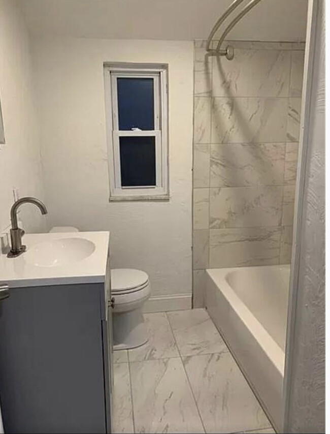 Newly remodeled Porcelin bathroom with new vanity, toilet, flooring, tub and shower surround. - 811 Killarney Dr