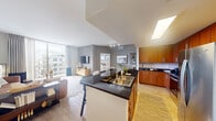 Located at 700 SW 78th Ave in Plantation, FL, this thoughtfully designed single-floor residence offers three bedrooms, two bathrooms, and a functional layout that maximizes every square foot. The open-concept kitchen and living area serves as the heart of the home, where warm wood cabinetry, dark granite countertops, and stainless steel appliances create a polished, contemporary kitchen. A peninsula with bar seating provides a casual dining option while keeping the cook connected to the living space. Natural light pours in through large floor-to-ceiling windows and a skylight, brightening the entire common area. The living room opens directly onto a private balcony, offering expansive outdoor views of the surrounding Plantation community. Light wood-style flooring runs throughout, adding warmth and continuity. The spacious primary bedroom features generous natural light, a walk-in closet with built-in shelving, and a distinctive accent wall that adds character. A second bedroom offers ample space and its own window views. The two bathrooms are finished with granite vanity tops, white cabinetry, and tiled tub-shower combinations. A dedicated hallway connects the private quarters seamlessly to the main living areas, completing this well-organized and stylish residence.