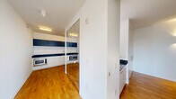 Located at 338 Third St in Jersey City's downtown district, this modern two-bedroom, two-bathroom residence offers a thoughtfully designed single-floor layout with clean lines and contemporary finishes throughout. Warm hardwood flooring flows consistently across the living areas and bedrooms, creating a cohesive and inviting atmosphere.

The open kitchen is outfitted with dark granite countertops, crisp white lower cabinetry, dark upper cabinets, a stainless steel sink, and full-size stainless steel appliances including a refrigerator and built-in microwave. The adjoining living area benefits from an open, airy feel with ample room to relax and entertain.

The bedrooms are bright and well-proportioned, with large multi-pane windows framing sweeping city views of the Jersey City skyline and surrounding neighborhood rooftops. Natural light pours in generously throughout the day. The primary bedroom includes a built-in wardrobe with floor-to-ceiling white panel doors and an adjacent vanity featuring a dark granite countertop and illuminated mirror.

Both bathrooms are finished in a modern style: one features gray tile flooring, a wall-mounted toilet, pedestal sink, and a glass-enclosed shower; the other offers a tiled tub-shower combination. The overall design is clean, minimal, and move-in ready.