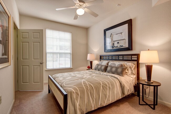 A cozy bedroom with ceiling fan and window overlooking the property - The Residence at Heritage Park