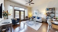This single-floor residence offers a thoughtfully designed open-concept layout that seamlessly connects the kitchen, dining, and living areas. The kitchen is a standout feature, equipped with rich dark-wood cabinetry, stainless steel appliances including a gas range, microwave, and French-door refrigerator, a subway tile backsplash, and a central island with a quartz countertop, undermount sink, and pendant lighting overhead. Bar seating at the island makes it equally suited for casual dining or entertaining. The living room is bathed in natural light from large French doors that open to a private balcony, offering outdoor views. Warm hardwood flooring flows throughout the main living areas, complementing the ceiling fan and clean, neutral-toned walls. Two spacious bedrooms provide comfortable retreats, each with large windows that invite natural light. The primary bedroom is accompanied by an en-suite bathroom featuring a dual-sink vanity with quartz countertops and dark cabinetry, tile flooring, and a full-size tub-shower combination with elegant marble-style tile surround. A second full bathroom mirrors the refined finishes found throughout, maintaining a cohesive aesthetic. Together, these spaces create a balanced and functional home with quality finishes at every turn.