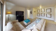 This single-floor residence offers a thoughtfully designed layout encompassing one bedroom and one full bathroom. The living room serves as the central gathering space, featuring plush carpeting, neutral walls, and a large sliding glass door that invites abundant natural light while providing outdoor views of surrounding greenery. The open feel of the room accommodates generous seating arrangements comfortably.

The galley-style kitchen is efficiently organized with warm oak cabinetry lining both sides, white countertops, tile flooring, and a full suite of appliances including a refrigerator and electric range. Ample cabinet storage runs from counter height to the ceiling, maximizing functionality.

The bedroom is a quiet, carpeted retreat with a notable window framing outdoor views, providing natural light and a connection to the surroundings. The room offers enough space for a full furniture arrangement.

The full bathroom features tile flooring, a combined tub and shower with a curtain surround, a toilet, and an oak vanity with a wide countertop, single sink, and a large mirror illuminated by a multi-bulb light bar above.

A dedicated in-unit laundry closet houses a stacked washer and dryer, adding everyday convenience to this well-rounded residence.
