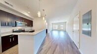 Located at 1 Mansfield Ave in Mansfield, MA, this thoughtfully designed 2-bedroom, 2-bathroom residence offers a comfortable and functional single-floor layout. The open-concept living and kitchen area is immediately welcoming, featuring durable wood-style flooring, crisp white walls, and an abundance of natural light streaming through large windows at the far end of the living room. The kitchen is well-equipped with rich dark-espresso cabinetry, granite-style countertops, stainless steel appliances including a refrigerator, electric range, and microwave, and a peninsula that doubles as a breakfast bar with pendant lighting above. Both bedrooms are generously proportioned, with the primary bedroom featuring hardwood-style flooring and dual windows, while the second bedroom is finished with plush carpeting and its own set of windows with natural views. Each of the two full bathrooms is finished with wood-look flooring, a full soaking tub with shower, and a dark-toned vanity. Additional conveniences include two closets, a dedicated utility room, and an in-unit laundry area. The overall ambiance is clean, modern, and move-in ready.