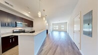 Located at 1 Mansfield Ave in Mansfield, MA, this thoughtfully designed 2-bedroom, 2-bathroom residence offers a comfortable and functional single-floor layout. The open-concept living and kitchen area is immediately welcoming, featuring durable wood-style flooring, crisp white walls, and an abundance of natural light streaming through large windows at the far end of the living room. The kitchen is well-equipped with rich dark-espresso cabinetry, granite-style countertops, stainless steel appliances including a refrigerator, electric range, and microwave, and a peninsula that doubles as a breakfast bar with pendant lighting above. Both bedrooms are generously proportioned, with the primary bedroom featuring hardwood-style flooring and dual windows, while the second bedroom is finished with plush carpeting and its own set of windows with natural views. Each of the two full bathrooms is finished with wood-look flooring, a full soaking tub with shower, and a dark-toned vanity. Additional conveniences include two closets, a dedicated utility room, and an in-unit laundry area. The overall ambiance is clean, modern, and move-in ready.