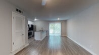 This single-floor unit offers a clean, modern aesthetic with an open-concept design that connects the living area and kitchen seamlessly. Wood-look plank flooring runs throughout the space, providing a warm and cohesive foundation across every room.

The kitchen is a standout feature, equipped with stainless steel appliances including a gas range, microwave, and refrigerator. White shaker cabinetry with a subway tile backsplash lines the walls, while a peninsula with a dark quartz countertop and an undermount sink adds both prep space and a natural divider between the kitchen and living area. A sliding glass door with vertical blinds floods the open living space with natural light and provides direct access to an outdoor area.

The bedrooms are well-proportioned, each featuring ceiling fans, wood-look flooring, and ample natural light from windows with outdoor views. One bedroom includes a closet with built-in shelving. An additional room with a ceiling fan and entry door offers flexible use.

The bathroom maintains the same modern finishes, with wood-look flooring, a white vanity, and a tiled shower surround. Throughout the unit, neutral gray walls and white trim create a bright, clean ambiance that complements the contemporary design.