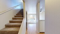 Located at 1450 Creekside Dr in Walnut Creek, CA, this two-story home offers two bedrooms and one bathroom across a well-organized layout. The main floor features warm hardwood flooring throughout the living and kitchen areas. The kitchen is designed with white cabinetry, light stone countertops, and a peninsula that opens to the main living space, creating a functional and connected flow. The living room is bright and airy, highlighted by a ceiling fan, large windows, and a sliding glass door that opens to a private outdoor patio area. Carpeted stairs lead to the upper floor, where both bedrooms are located. The primary bedroom is a comfortable size and features a closet with built-in shelving, carpeted flooring, and a window with outdoor tree views. The second bedroom is similarly carpeted and bathed in natural light from a large window. A full bathroom on the upper floor includes a shower-tub combination with grab bars and clean white tile. Each bedroom benefits from dedicated closet space, and a hallway connects the upper-level rooms. The overall aesthetic is clean and neutral throughout, with light-toned walls and an abundance of natural light creating a welcoming ambiance across both floors.