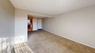 Located at 2703 S Topeka St in Wichita, Kansas, this 2-bedroom, 1-bathroom unit offers a practical and well-organized single-floor layout. The living room is a comfortable, open space with plush carpeting, neutral beige walls, and a large sliding glass door fitted with vertical blinds that allows natural light to pour in and provides direct outdoor access. Adjacent to the living area, the kitchen features warm wood cabinetry, light countertops, tile flooring, a double-basin sink, a white electric range, and a dishwasher — all centered around a window that brings in additional natural light. Both bedrooms are carpeted and finished with neutral tones. The primary bedroom includes a window with blinds, while the second bedroom features a sliding closet door for convenient storage. A dedicated laundry area with built-in shelving and washer/dryer hookups adds functional value. The full bathroom is finished with tile flooring and includes a combined tub and shower unit with built-in shelving, alongside chrome hardware accents. Textured ceilings are found throughout, contributing to the unit's consistent and clean aesthetic.