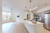 Located at 210 Spring St in Winchester, Virginia, this thoughtfully designed 2-bedroom, 2-bathroom residence offers a well-planned single-floor layout that maximizes comfort and functionality. The open-concept kitchen and living area serves as the heart of the home, featuring light hardwood-style flooring, crisp white walls, and abundant natural light. The kitchen is well-appointed with taupe shaker-style cabinetry, white quartz countertops, a large center island with an undermount sink, stainless steel appliances including a refrigerator, range, microwave, and dishwasher, and stylish pendant lighting overhead. The adjoining living area is bright and airy, with a ceiling fan and a large window overlooking the exterior courtyard. Both bedrooms offer plush wall-to-wall carpeting, ceiling fans, and dedicated closet space, with the primary bedroom providing a generous footprint. The two bathrooms are finished with granite-topped vanities and wood-toned cabinetry; one features a walk-in shower, while the other offers a full shower setup. Two closets provide ample storage throughout. The overall ambiance is clean, contemporary, and move-in ready.