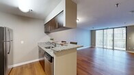 Located at 9890 Washingtonian Blvd in Gaithersburg, MD, this 1-bedroom, 1-bathroom residence offers a thoughtfully designed layout across a single floor. The open-concept kitchen is a standout feature, showcasing granite countertops, rich dark wood cabinetry, stainless steel appliances — including a refrigerator, range, microwave, and dishwasher — and a peninsula with bar seating for two, making it ideal for casual dining and entertaining. Hardwood flooring flows seamlessly through the kitchen and living areas, adding warmth and continuity to the space. The living room is bright and spacious, anchored by large sliding glass doors dressed with vertical blinds that invite natural light and provide access to an outdoor view. The generously sized bedroom features soft carpeting, a large window overlooking greenery, a closet, and direct access to the bathroom. The bathroom is clean and functional, featuring a dark wood vanity with a white countertop, an over-vanity mirror, wall-mounted storage cabinet, and a tiled shower-tub combination. Neutral tones throughout create a calm and cohesive aesthetic, making this a comfortable and practical living space.