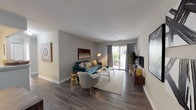 This single-story residence offers a thoughtfully designed layout across several well-defined living spaces. The living room serves as the centerpiece of the home, featuring dark hardwood-style flooring, neutral gray walls, and a sliding glass door that fills the space with natural light while providing access to an outdoor area with greenery views. The open arrangement accommodates both a seating area and a media console, creating a versatile and comfortable gathering space.

The kitchen is equipped with white cabinetry, white countertops, and a full suite of stainless steel appliances, including a refrigerator, electric range, and dishwasher. Light wood-tone flooring ties the space together with a clean, functional aesthetic.

Two well-sized bedrooms each feature plush carpeting, neutral walls, and windows that allow natural light to filter through. Both rooms offer ample space for full furniture arrangements.

The two bathrooms maintain a consistent design with white vanities, large mirrors, and hardwood-style flooring. One bathroom features a shower-tub combination, while the other presents a more compact layout suited as a secondary bath. Together, the spaces offer a cohesive, move-in-ready environment.