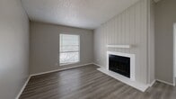 Located at 500 E Loop 820 in Fort Worth, TX, this 2-bedroom, 2-bathroom residence offers a well-organized single-floor layout designed for comfortable everyday living. The entryway opens through a hallway into the main living areas, where wood-look flooring in a warm gray tone flows consistently throughout the home. The living room serves as a central gathering space, highlighted by a white shiplap-accented fireplace wall that adds a charming focal point, complemented by a window that brings in natural light and outdoor views. The kitchen features white cabinetry with contemporary hardware, light quartz-style countertops, a classic subway tile backsplash, and black appliances including a refrigerator and range. Both bedrooms offer a calm, neutral palette with gray walls, wood-look flooring, and windows fitted with blinds that provide natural light and exterior views. The primary bedroom includes two closets, offering ample storage. Each bathroom is outfitted with a full tub-shower combination and built-in shelving for added convenience. Textured ceilings are present throughout the home. The layout connects efficiently through a central hallway, making the space feel organized and cohesive from entry to the private bedroom areas.