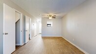 Located at 10126 E Boston St in Wichita, Kansas, this single-story unit presents a clean, neutral aesthetic with a practical layout designed for comfortable everyday living. The main living area features warm wood-look flooring, soft gray walls, and a ceiling fan with integrated lighting, creating a bright and airy atmosphere. A hallway extends from the living area, lined with multiple doors offering access to closets and additional rooms, providing generous storage options throughout.

The bedrooms are finished with plush carpet flooring and ceiling fans, contributing to a cozy feel. One bedroom benefits from a large window that frames views of mature trees and greenery outside, allowing ample natural light to fill the space. Additional rooms also feature the same wood-look flooring found in the main living areas.

The galley-style kitchen is well-appointed with white cabinetry, granite-look countertops, and black appliances including a range, microwave, refrigerator, and dishwasher. Wood-look flooring continues throughout the kitchen, maintaining a cohesive look.

The bathroom is efficiently designed, featuring a white vanity with storage, a mirror, and a full shower-tub combination with brushed nickel fixtures. Wood-look flooring completes the space with a clean, polished finish. Overall, the unit offers a functional and well-maintained interior throughout.