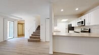 This well-maintained two-story home offers a clean, modern aesthetic throughout, with thoughtful updates and a bright, welcoming atmosphere. The main level features light wood-style vinyl flooring that flows through the open living and dining areas, creating a cohesive and airy feel. A sliding glass door on the main floor allows natural light to pour in and provides access to the exterior. The kitchen is a standout feature, boasting white shaker-style cabinetry, a neutral tile subway backsplash, stainless steel appliances including a refrigerator, range, and over-the-range microwave, and a peninsula with counter seating. A skylight above the kitchen adds additional natural light to the space. A half bathroom on the main level features a marble-topped vanity and light flooring for a clean, polished look. Carpeted stairs lead to the upper level, where the bedrooms are finished with plush carpet flooring, offering comfort and warmth. The upper-level bathroom is well-appointed with a white vanity, marble-style countertop, and a glass-door walk-in shower with brushed gold hardware. Textured ceilings are consistent throughout, and recessed lighting provides ample illumination across the home. A ceiling fan in one of the upper rooms adds both function and comfort to the space.